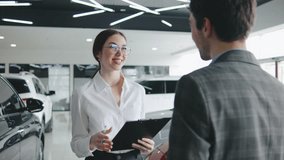 Sales representative discusses features and financing options with a potential buyer at a modern car dealership showroom - Powered by Shutterstock - Get 15% off with code: PIKWIZARD15