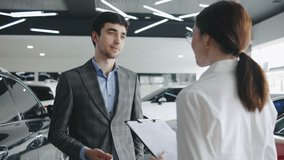 Client consulting with a sales associate in a modern car dealership during the day while considering a vehicle purchase and discussing options - Powered by Shutterstock - Get 15% off with code: PIKWIZARD15