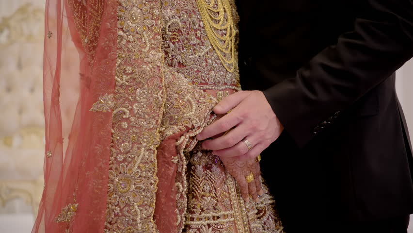  Close up view of couple standing together, holding hands, dressed in traditional red Indian clothes, Elements of Hindu wedding.