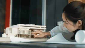 Closeup of asian young beautiful architect engineer looking at project plan with model placed on table. Professional project manager analysis house structure. Business design concept. Manipulator. - Powered by Shutterstock - Get 15% off with code: PIKWIZARD15