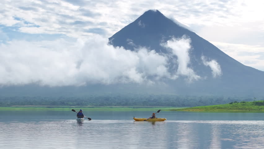 Kayak at dawn in the serene Laguna de Arenal, surrounded by mist and clouds, while admiring the majestic Arenal Volcano, a gem of Costa Ricas landscape
