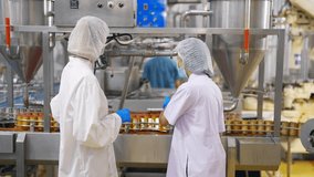 Canned food manufacturing factory industry. Quality control officer inspecting and sampling sardines in tomato sauce packed in aluminum cans move along automated conveyor belt in production line. - Powered by Shutterstock - Get 15% off with code: PIKWIZARD15