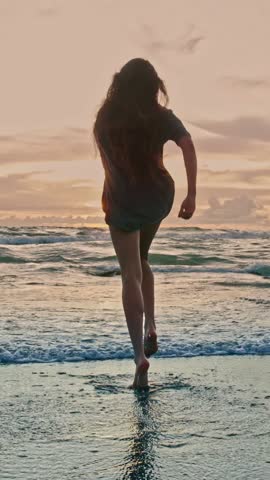 Beautiful Woman Running on Sandy Beach and Wet Legs Stepping on Water. Alone Adult Girl at Bright Scenic Sea Going Swim or Splash. Modern Romance of Ocean Bathing and Gorgeous Summer Sky at Shoreline