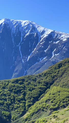 Trinity Church of Gergeti on the background of snow-capped mountains. View of the mountain peaks near Stepantsminda, Georgia. The ancient Christian church of Gergeti at the foot of Mount Kazbek. 4К