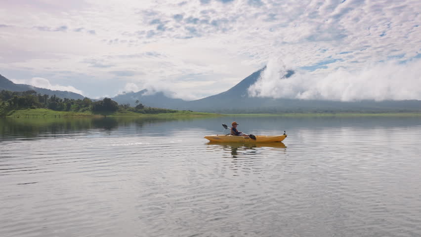 Immerse yourself in the stunning beauty of Laguna de Arenal and Volcan Arenal as a father and son enjoy kayaking at sunrise, making unforgettable memories together