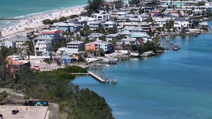 Port and pier on one side and sandy beach with people on other of Bradenton Town,USA. Aerial wide shot. Houses, homes and hotels in city of Florida during sunny day.