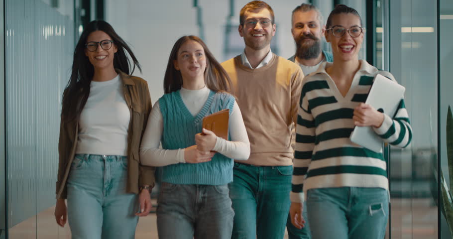 Business team in a modern open space startup office walking together. Diverse group of businesspeople smiling while having a discussion. Successful mixed race colleagues collaborating on a new project
