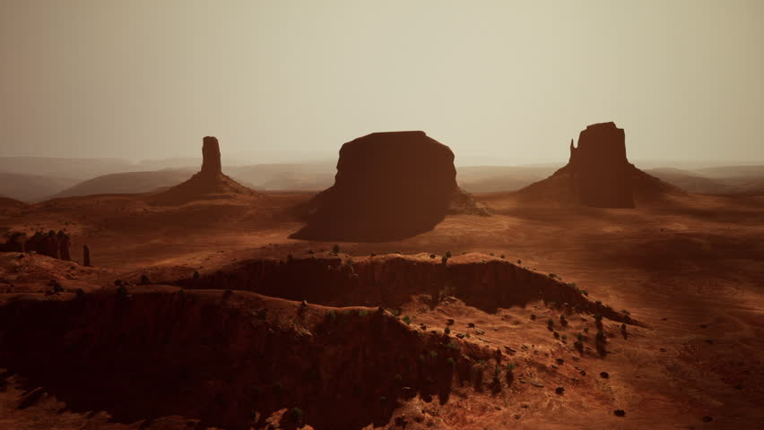 Golden hour casts a warm glow over Monument Valley, highlighting the dramatic rock formations and vast desert landscape, creating a breathtaking view.