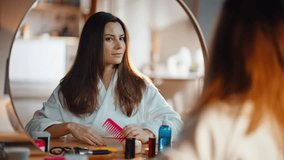 Woman combing hair in mirror doing morning haircare routine at home closeup. Happy long-haired brunette brushing healthy hairstyle sitting apartment bedroom. Smiling young lady caring natural beauty. - Powered by Shutterstock - Get 15% off with code: PIKWIZARD15