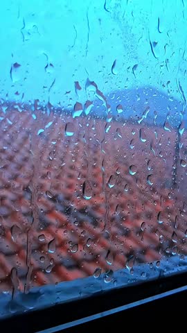 Raindrops on the window,water flowing on window glasss.Closeup raindrops on the window glass with water splash.Rain sounds for dramatic background,story,ASMR.Vertical video concept