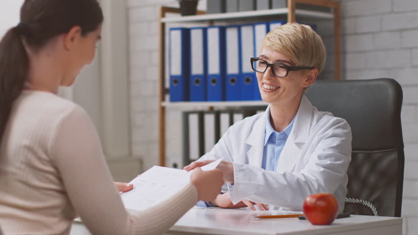 A healthcare professional discusses nutrition with a lady patient in a modern clinic. The dietitian is reviewing dietary plans and providing guidance on healthy eating choices.