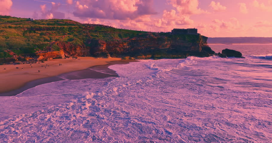Dramatic aerial view of deep blue ocean waves crashing against a rocky coastline at sunset golden hour light enhances this serene tropical seascape, perfect for travel, vacation, and nature themes