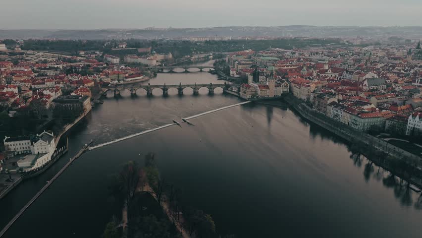 Aerial cinematic drone view of Prague city. Vltava river, famous bridges, historical architecture and old town panorama. Beautiful European cityscape, popular tourist destination.