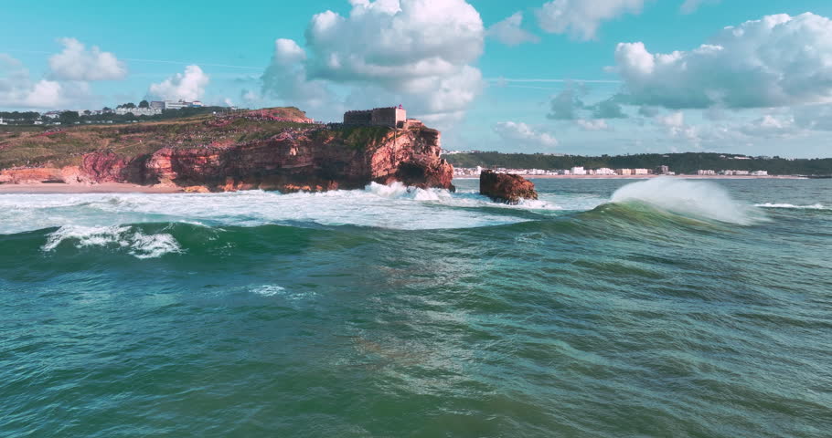 Dramatic aerial view of deep blue ocean waves crashing against a rocky coastline at sunset golden hour light enhances this serene tropical seascape, perfect for travel, vacation, and nature themes