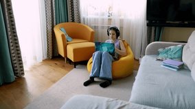 Young girl sits on bean bag chair enjoying music while using laptop in cozy living room - Powered by Shutterstock - Get 15% off with code: PIKWIZARD15