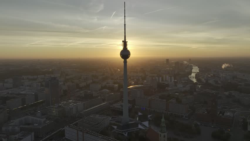 An aerial view of Berliner Fernsehturm at sunset, highlighting its sleek modern top structure, with the sprawling cityscape stretching beneath