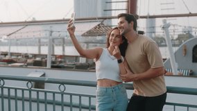 Portrait of affectionate Latin American couple takes selfie on smartphone against large yacht. Joyful Hispanic girlfriend and boyfriend create content for social media on vacation - Powered by Shutterstock - Get 15% off with code: PIKWIZARD15