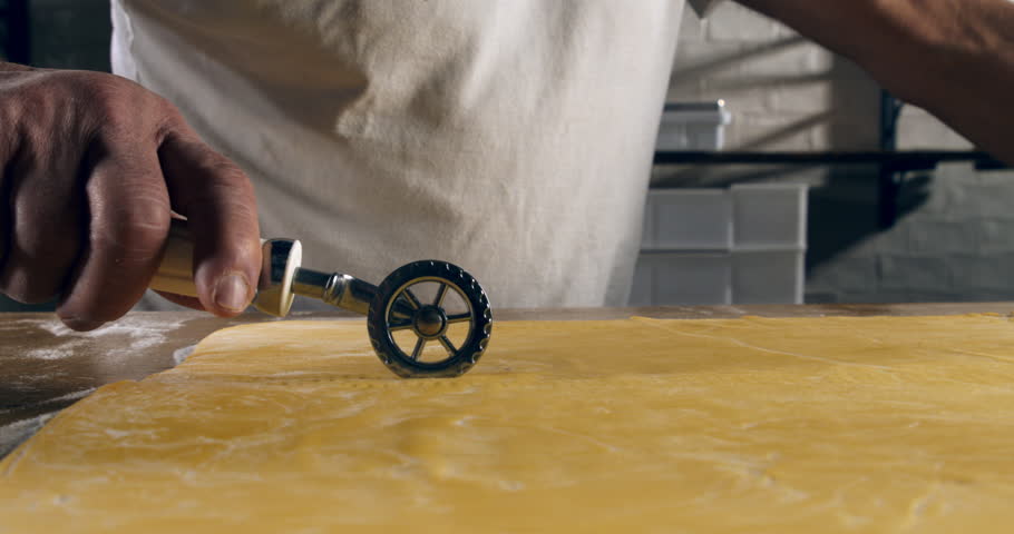 Super Slow Motion of Traditional Pasta Cutter Tool in Use to Shape Fresh Homemade Dough – Close-Up of Hands Crafting Artisan Pasta Strips in Rustic Italian Kitchen Setting at 1000 fps.