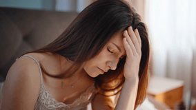 Sleepy woman suffering headache waking up in cozy home bed closeup. Unhappy lady feeling head pain after early wakeup in apartment bedroom. Sad young brunette experiencing health problem at morning. - Powered by Shutterstock - Get 15% off with code: PIKWIZARD15