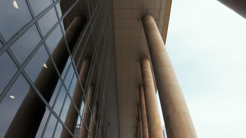 Showcase the stunning blend of tall columns and sleek glass windows in this captivating modern architecture video, highlighting urban design and structural elegance artistically