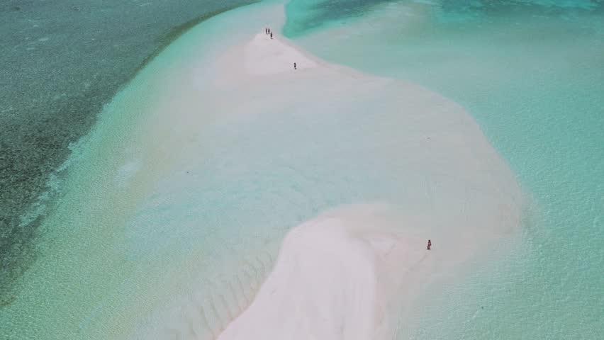 Aerial view of sandbank near Thulusdhoo island.Maldives.Group of people walking on white sandy sandbank at hot sun day.Slow motion video