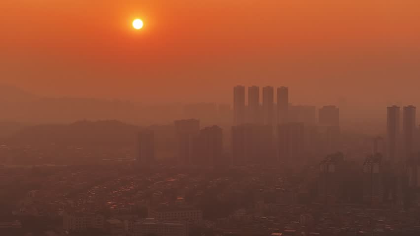 Evening city toxic smog. Air pollution urban environment. Aerial top above drone view. Orange sunset. Consequences forest fires. Global warming problem. Ecology issue. Fog enveloped town. Dirty smoke.