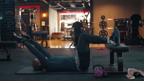 Caucasian man exercises on a yoga mat at gym. Male fitness model performing abs crunch at fitness center - side view - Powered by Shutterstock - Get 15% off with code: PIKWIZARD15