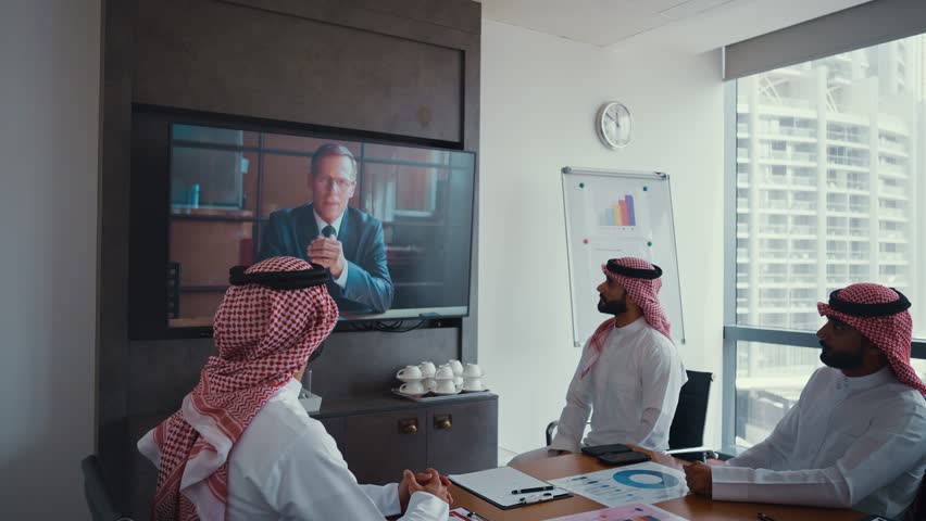 Cinematic video of a group of businessmen from Saudi arabia during an corporate meeting in an office. Mixed business team making a video call on the screen.