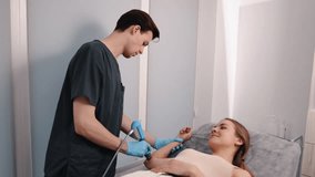 Spine care, Spinal therapy, Manual therapy. Chiropractor in dark scrubs and gloves is using percussion massager on female patient's arm while she lies on treatment table. - Powered by Shutterstock - Get 15% off with code: PIKWIZARD15