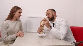 explaining knee, clinical anatomy, patient explanation. Healthcare provider explains knee structure using model during consultation with woman in clinic. - Powered by Shutterstock - Get 15% off with code: PIKWIZARD15