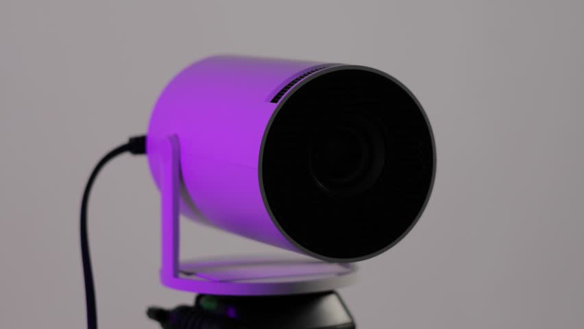 Close up, lens of modern wi-fi video-projector with lighting blue light. Video or photo presentation and home movie watching. 4k footage.