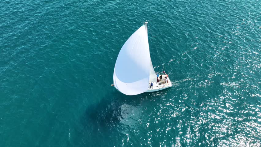 Aerial drone cinematic video of beautiful sail boat with white sails sailing in deep blue open ocean sea
