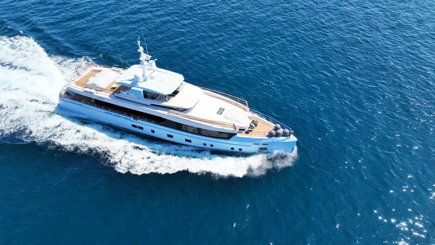 Aerial drone tracking video of beautiful modern super yacht with wooden deck cruising in high speed in Aegean deep blue sea