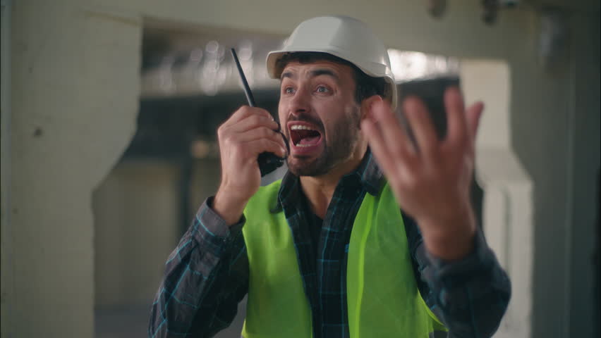 Angry Caucasian man talking shouting scream on walkie talkie radio device furious male contractor mad guy showing hand wrist late waiting builder building repairman annoyed foreman engineer architect