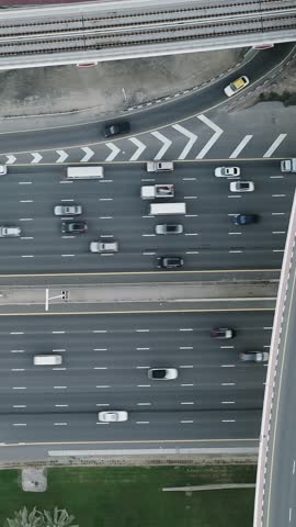 High-angle aerial top view of dense traffic flowing on multilayered highways and overpasses in Dubai at rush hour. Modern urban infrastructure, transport network, and daily city commute concept