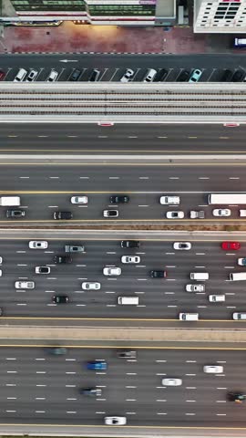 High-angle aerial top view of dense traffic flowing on multilayered highways and overpasses in Dubai at rush hour. Modern urban infrastructure, transport network, and daily city commute concept