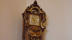 Refined wooden grandfather clock displaying gold details and moon phase, pendulum swinging softly against neutral wall inside high end residential interior - Powered by Shutterstock - Get 15% off with code: PIKWIZARD15