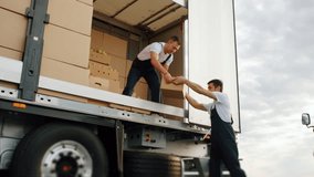 Workers loading delivery truck. Transportation of food, concept of carriage on lorry. Shipment order of foodstuff for sale. Men carry and sort cardboard boxes of fruits and vegetables for supplier. - Powered by Shutterstock - Get 15% off with code: PIKWIZARD15
