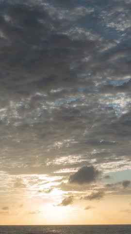 The sunrise sky transforms rapidly, clouds dancing in a time-lapse spectacle. A burst of colors emerges, painting the canvas of dawn. Nature concept. Timelapse.vertical style