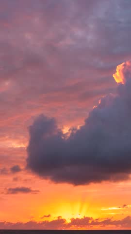 The sunset sky transforms into a breathtaking canvas of vibrant hues. Wispy clouds gracefully dance, painting a mesmerizing timelapse spectacle. Time-lapse. Nature concept. 4K ,Vertical video