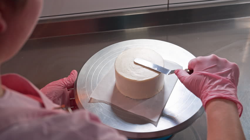 Pastry chef leveling cake sides with cream. Confectioner working with spatula. - Powered by Shutterstock - Get 15% off with code: PIKWIZARD15