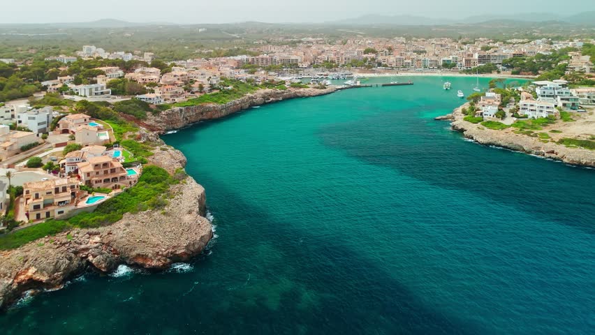 Aerial view of Porto Cristo resort town in Mallorca, Balearic Islands, Spain. Scenic coastal town in Cala Manacor bay with luxury villas, a natural harbor, and yachts on the Mediterranean Sea