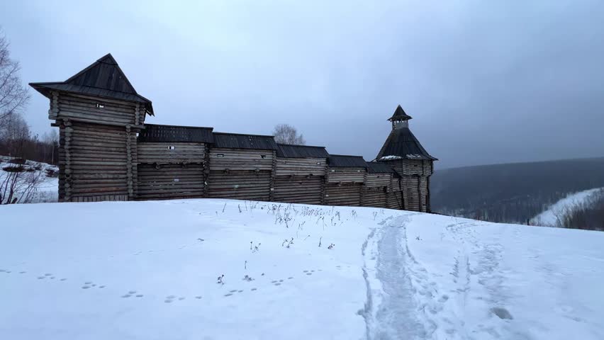 A log fortress wall covered with snow after a blizzard. Scenery for the film "The Heart of Parma" among snow-covered forests, hills and mountains in Perm Krai, Russia. The crooked cross in the Lip.4K