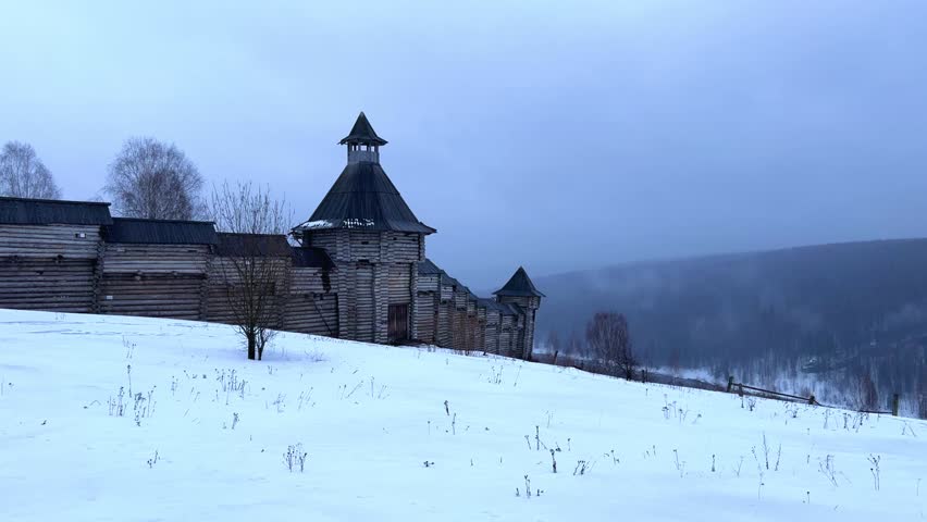 A log fortress wall covered with snow after a blizzard. Scenery for the film "The Heart of Parma" among snow-covered forests, hills and mountains in Perm Krai, Russia. The crooked cross in the Lip.4K
