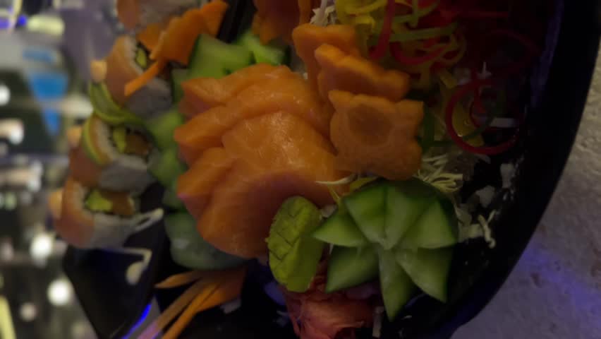 Seth sushi on a black background.Menu of the Japanese restaurant. Several sushi lined on a plate decorated with a decor of red berries, a flower and leaves