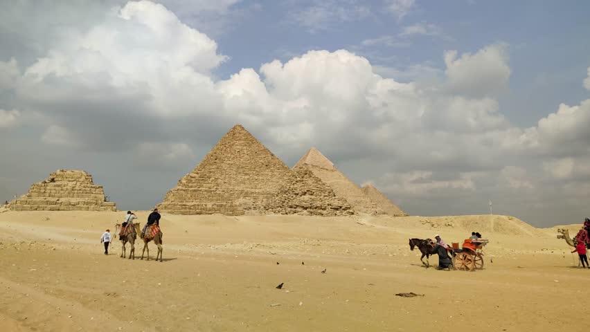 Giza, Egypt - March 9, 2025:  Giza Pyramid Complex in Egypt, view from the desert with tourist on a camel ride trip around the pyramids.