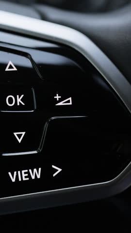 Vertical Video of Close-up view of car interior. View of steering wheel of car control music. Driver pressing volume button of car radio on steering wheel. Turns up the volume of the music in the car
