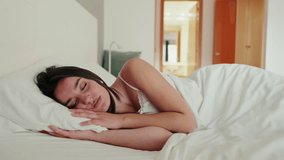 Serene young woman sleeping soundly in her comfortable bed, embracing a peaceful slumber. The white sheets and pillows create a clean and cozy atmosphere. - Powered by Shutterstock - Get 15% off with code: PIKWIZARD15