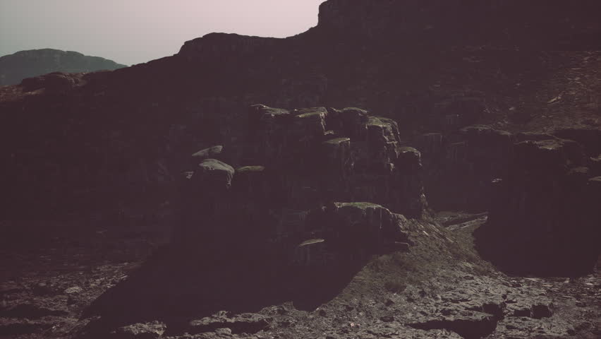 A large rock formation dominates the foreground with a majestic mountain visible in the background under a clear sky.