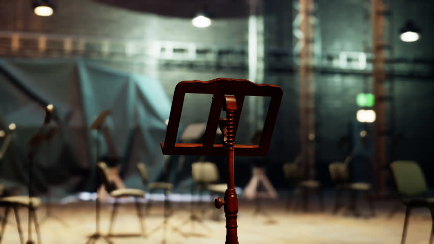 A wooden music stand stands alone in the center of an aged opera house, surrounded by empty chairs. The atmosphere is filled with anticipation for the evenings performance.